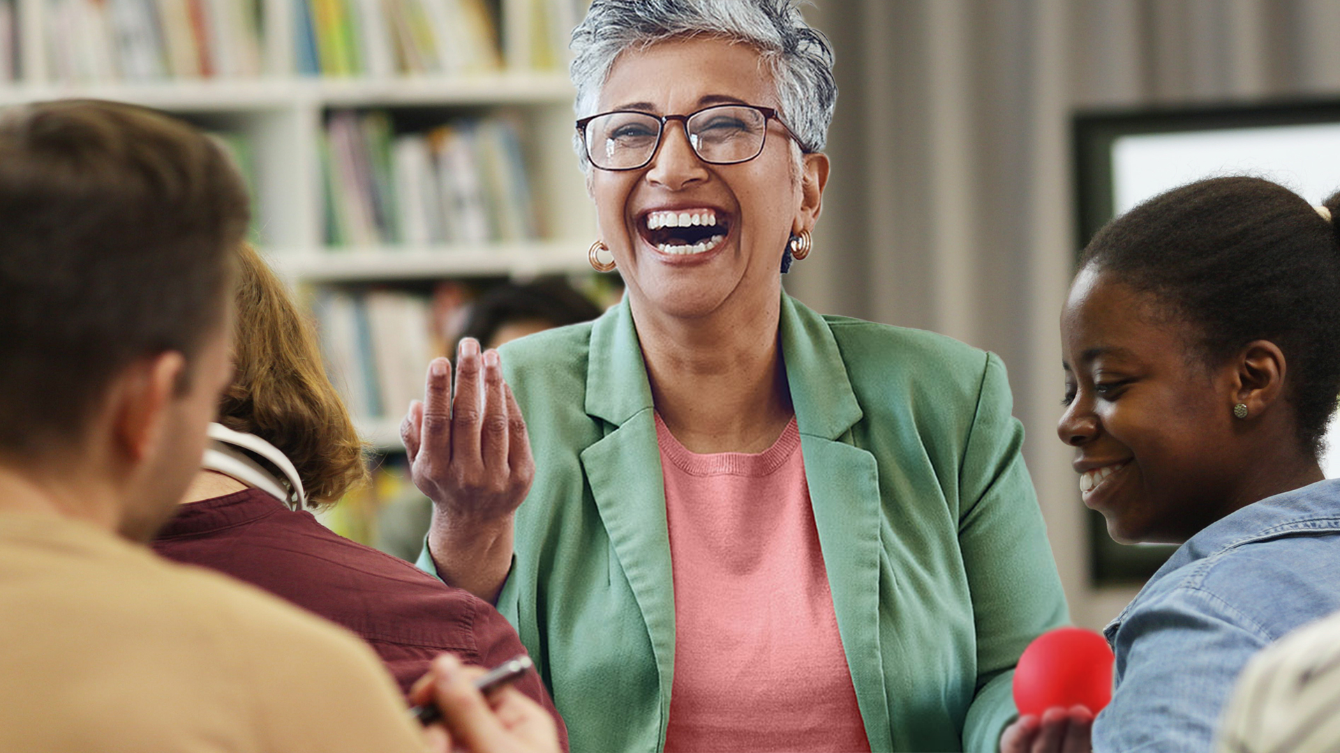 Eine lachende Lehrerin steht vor einer Klasse.