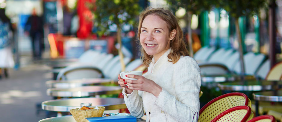 Eine Frau sitzt in einem Café und hält eine Tasse in den Händen