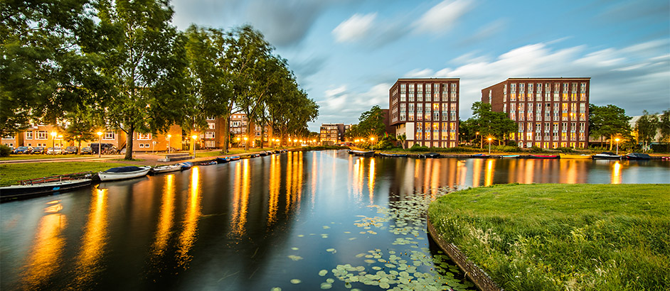 Kanal in den Niederlanden mit modernen Bürogebäuden im Hintergrund.